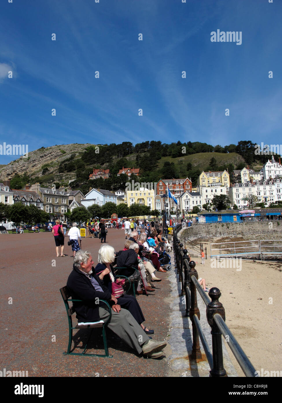 La Gente seduta sul lungomare di Llandudno Galles più grande stazione balneare il Galles del Nord Foto Stock