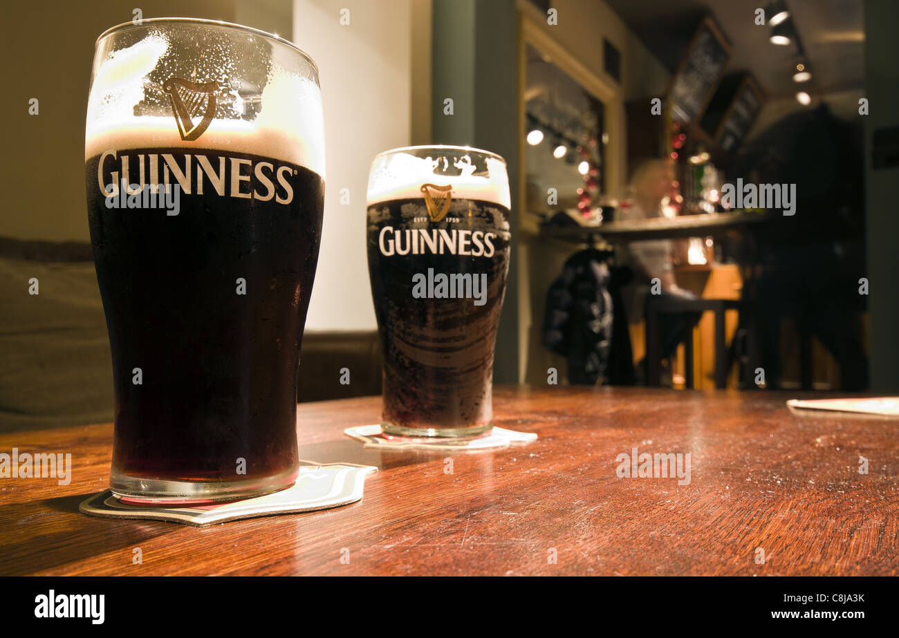 Pinte di birra Guinness alla tabella in un pub inglese Foto Stock