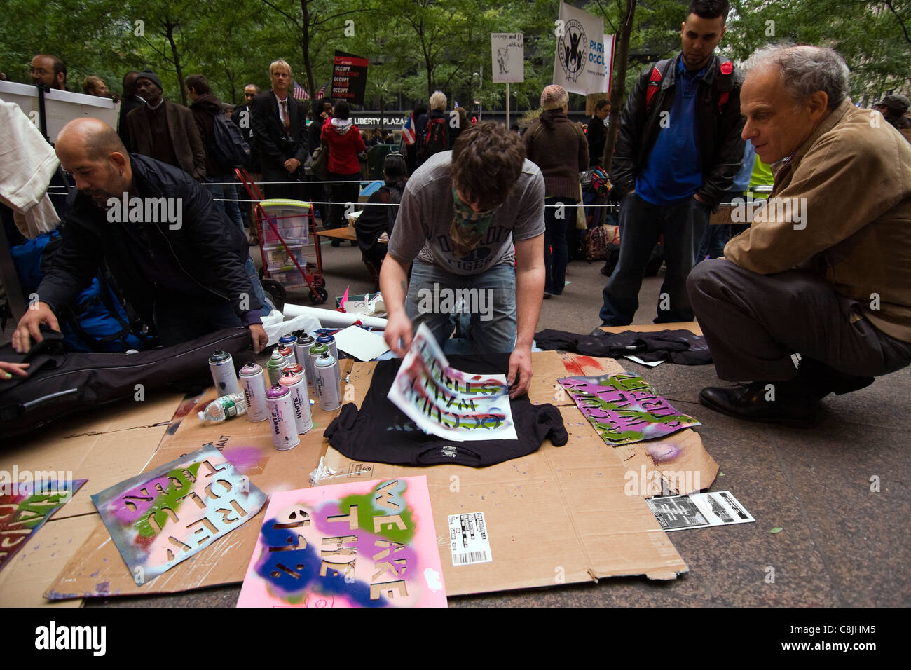 Occupare Wall Street protester verniciatura a spruzzo "occupare WALL STREET" su una T-shirt nera all'interno di Zuccotti Park Foto Stock