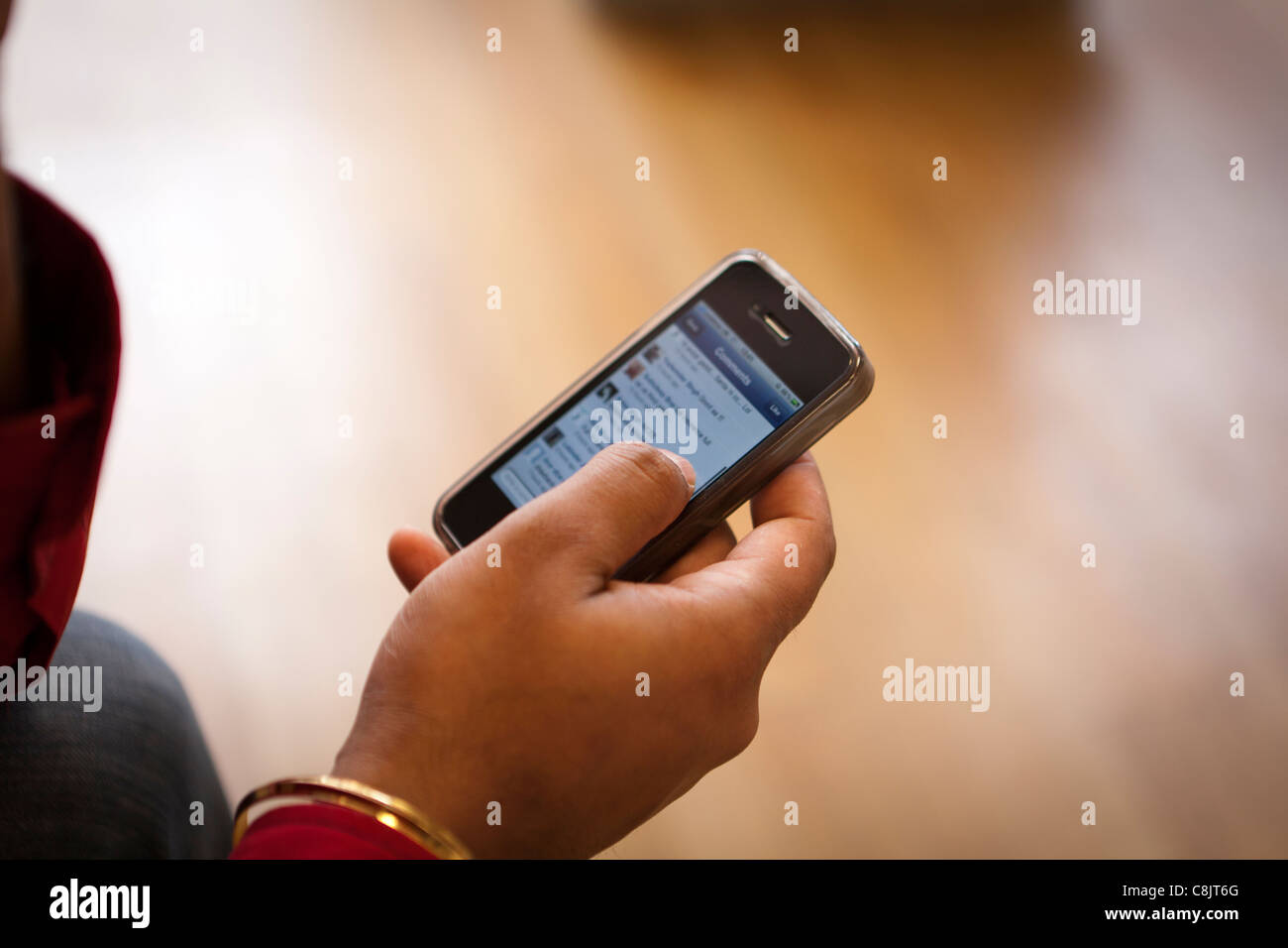Persona che controlla i siti di social networking su un iphone 4S Foto Stock