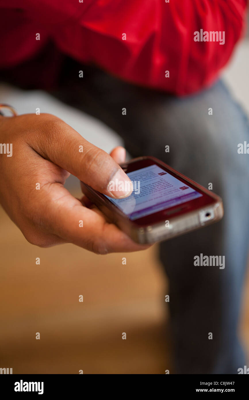 Persona che controlla i siti di social networking su un Iphone 4s Foto Stock