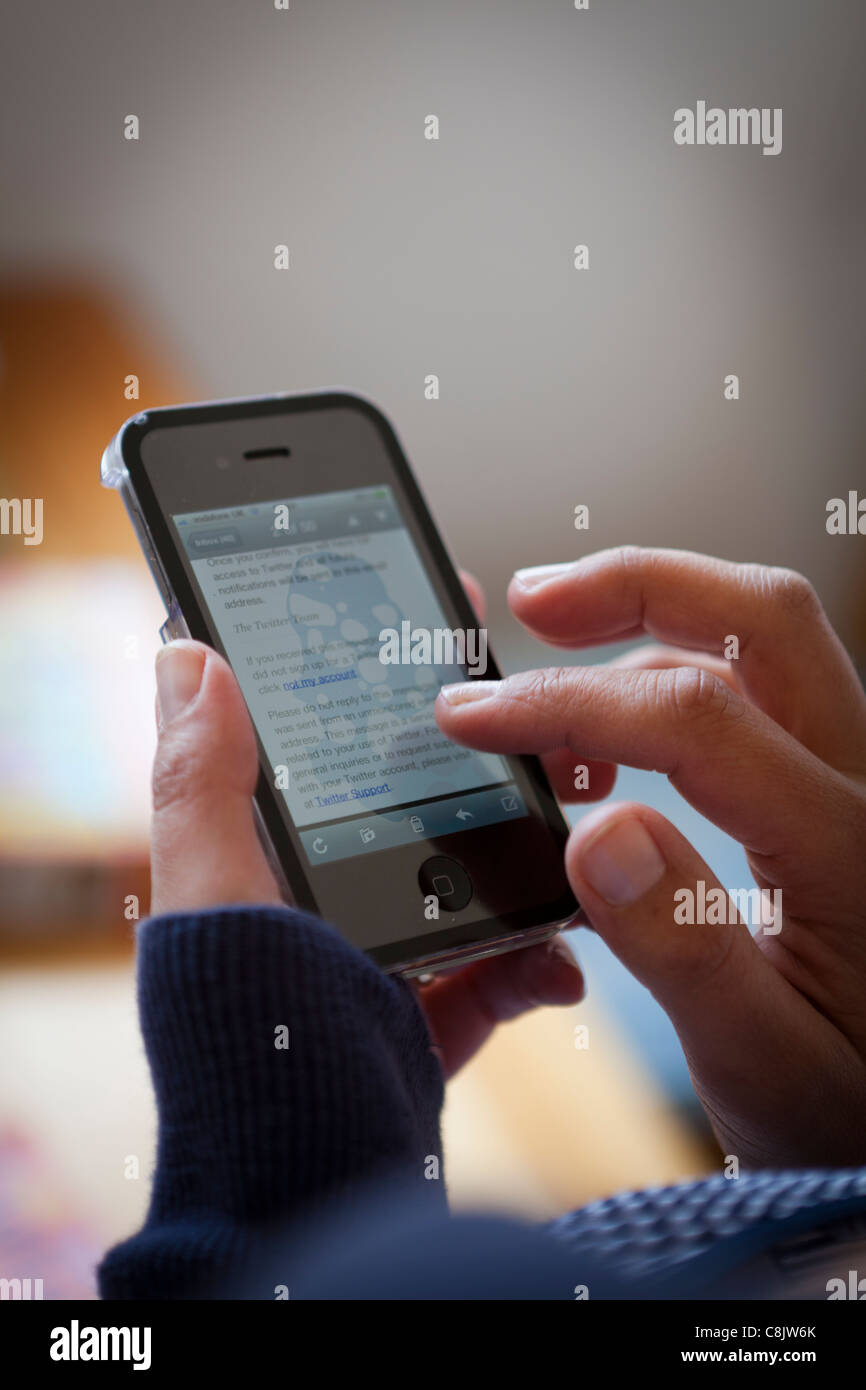 Persona che controlla i siti di social networking su un telefono 4s Foto Stock