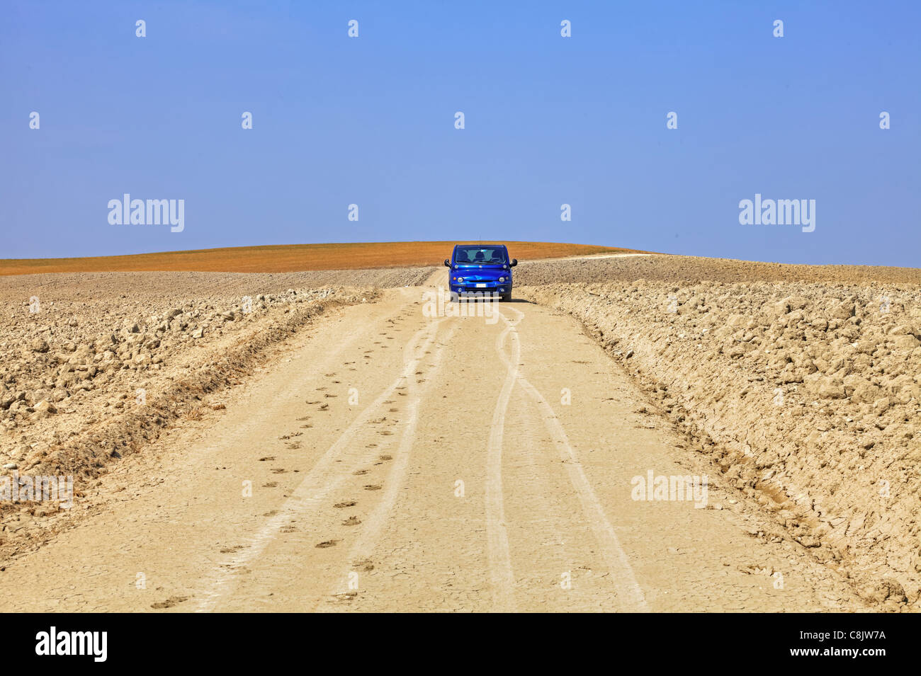 Un auto blu in mezzo ai campi di raccolta della Toscana Foto Stock