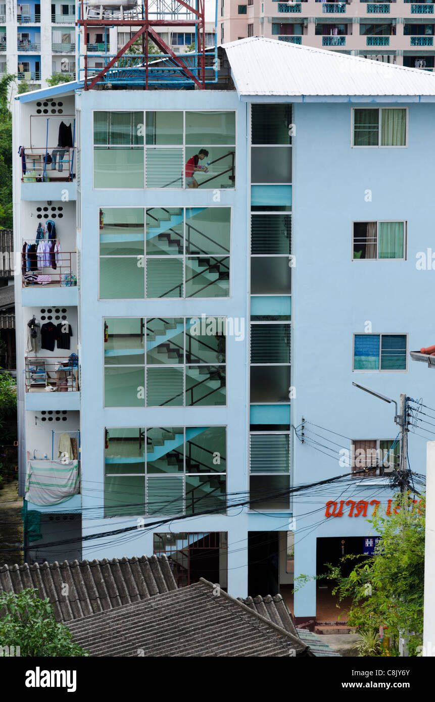 Cinque piani di luce blu appartamento edificio con grandi finestre di vetro che mostra 2 persone salire a piedi a scala in Chiang Mai Thailandia Foto Stock