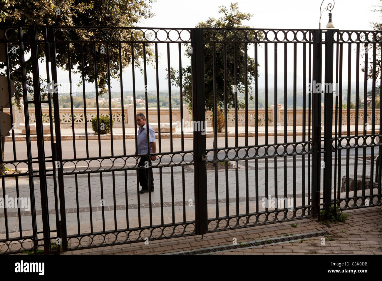 Uomo che cammina passato ferro battuto park gate a Palestrina Foto Stock