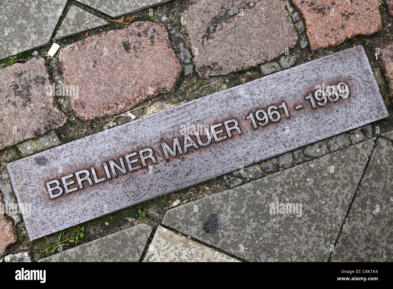 Una lapide in terra segna il contorno del demolito il muro di Berlino a Berlino, Germania. Foto Stock