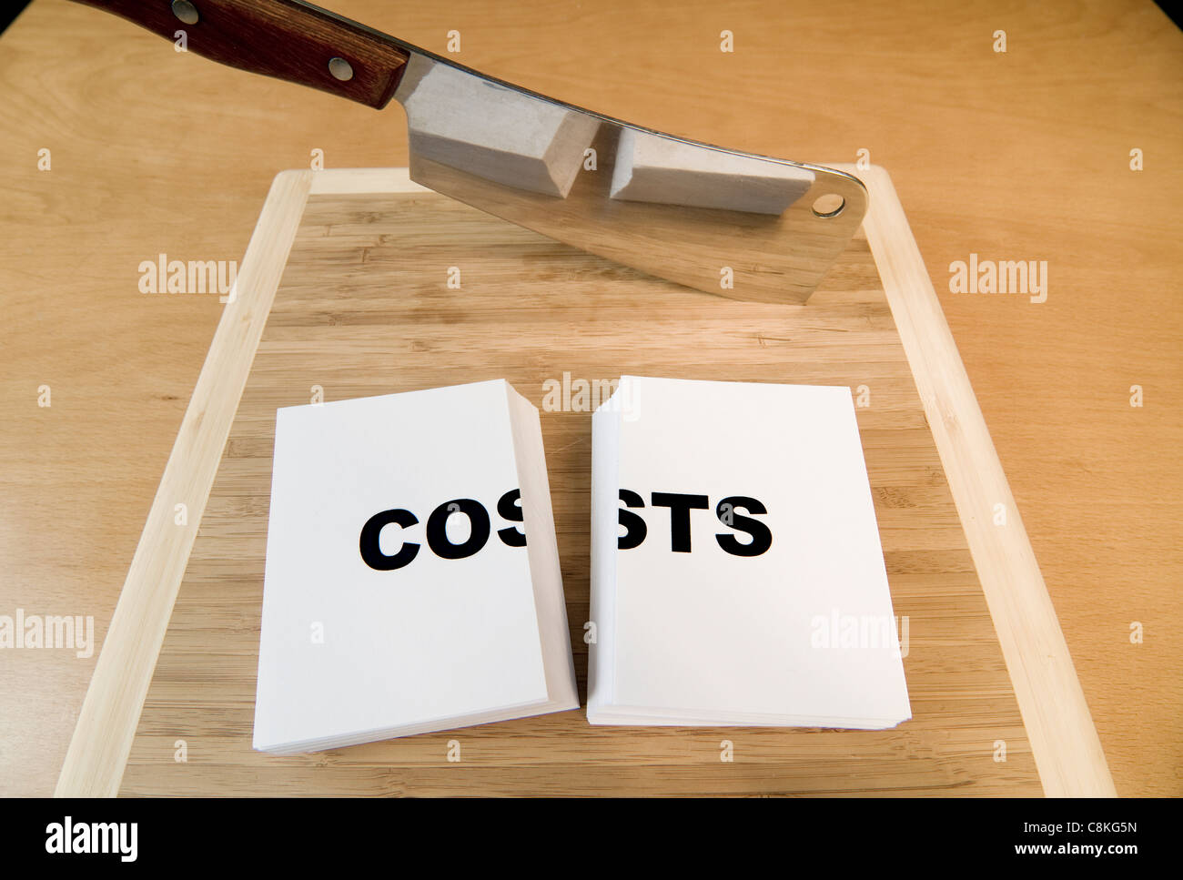 Il taglio dei costi negli affari o le finanze personali con un cleaver. Foto Stock