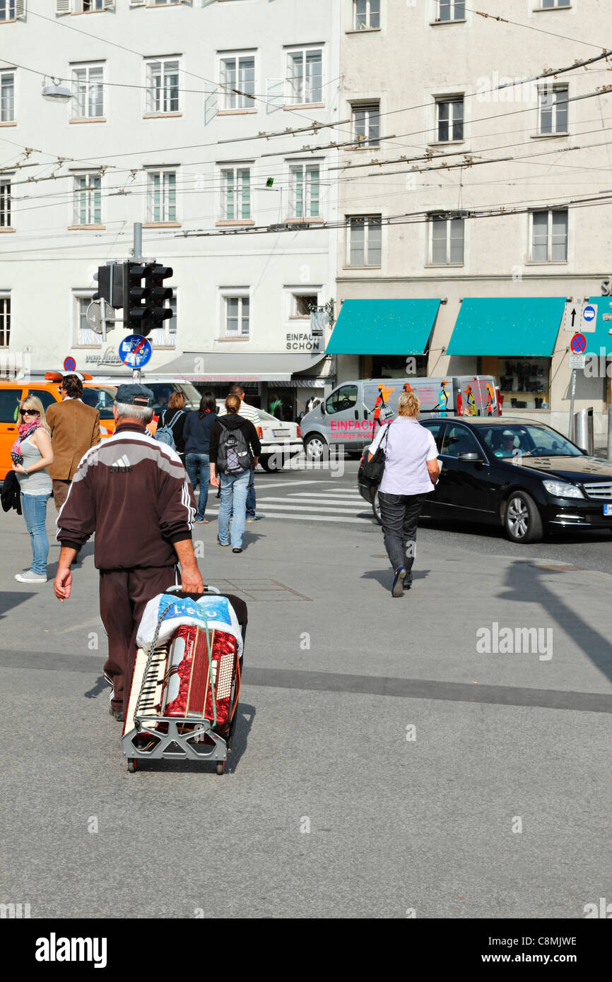 Suonatore ambulante di strada con la sua fisarmonica a piano su un tiro lungo il carrello, Salzburg Austria Foto Stock