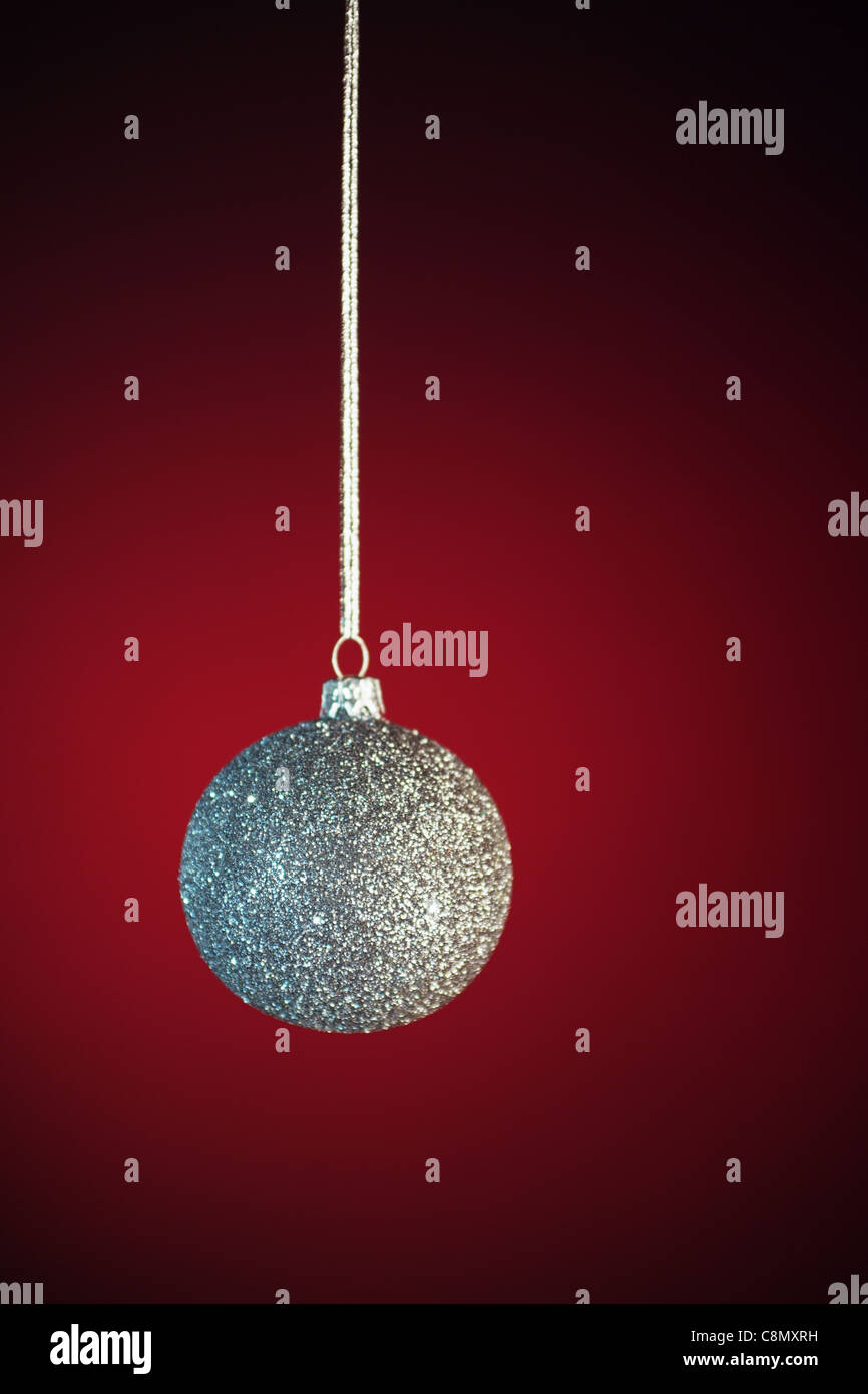 Argenteo Pallina natale su sfondo rosso, offuscata, con fuoco selettivo sulla glassa. Foto Stock