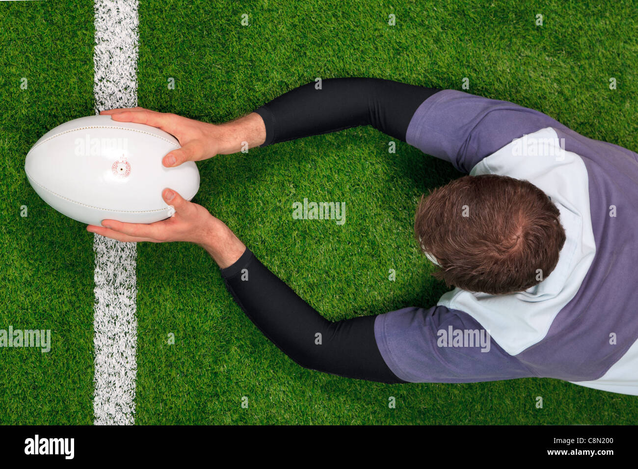 Foto aerea di un giocatore di rugby immersioni subacquee al di sopra della linea di cliente a provare con entrambe le mani tenendo la palla. Foto Stock