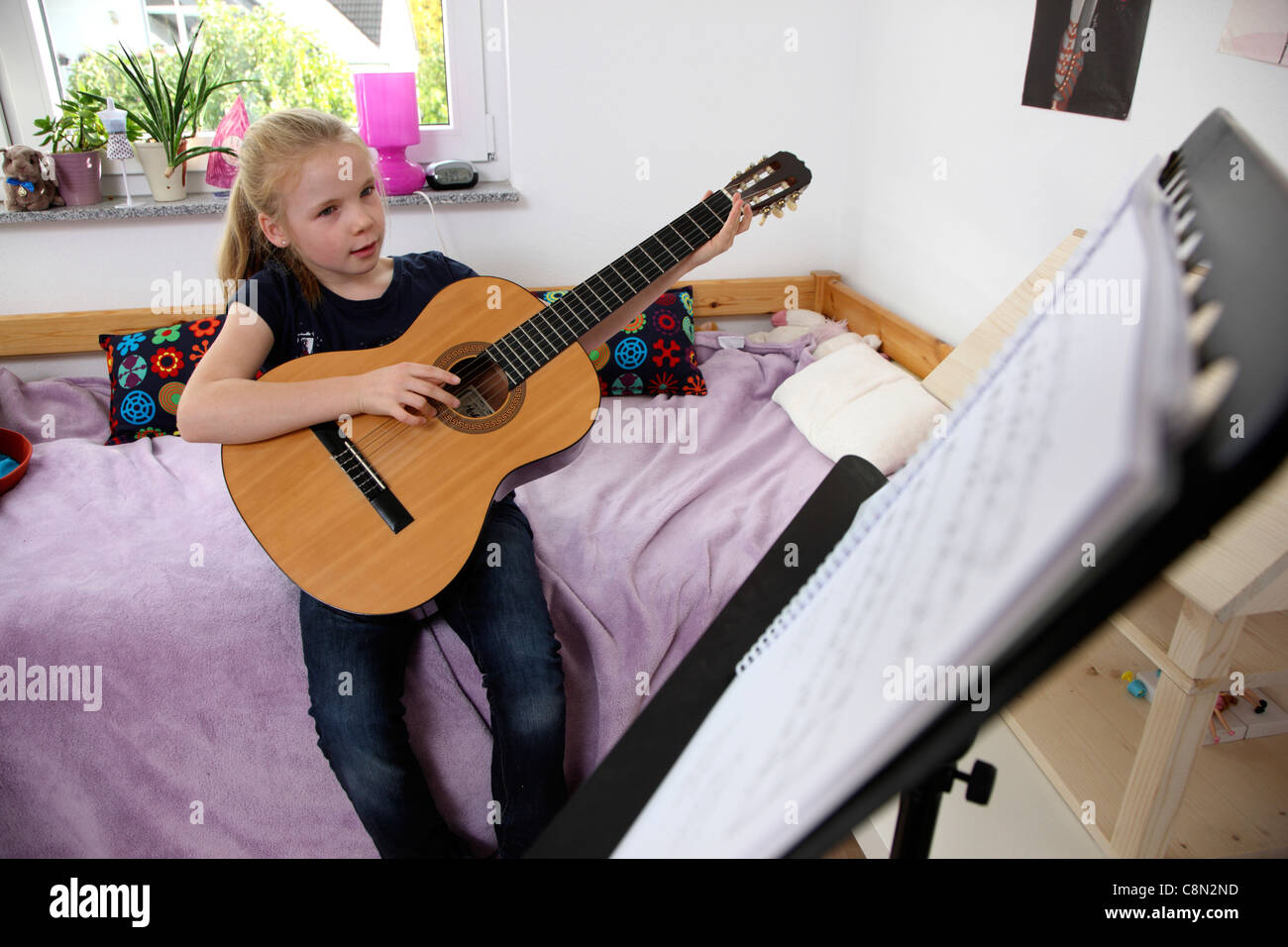 Ragazza, 10 anni, suonare la chitarra, a casa, imparare a suonare lo strumento. Foto Stock