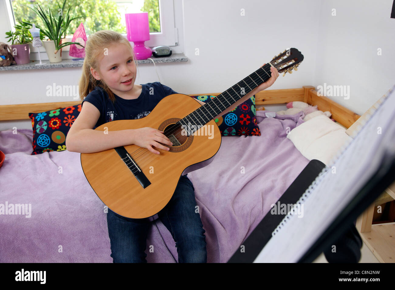 Ragazza, 10 anni, suonare la chitarra, a casa, imparare a suonare lo strumento. Foto Stock
