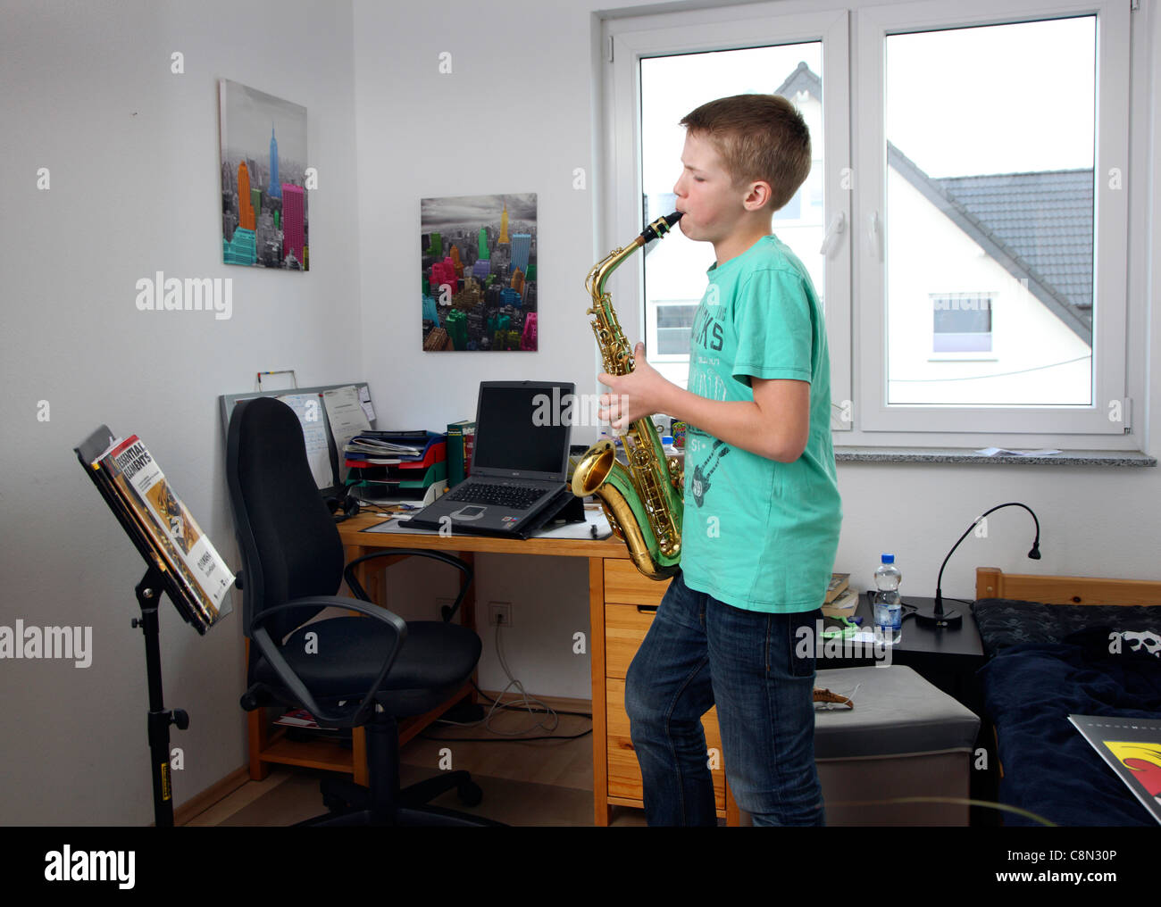 Il ragazzo, 13 anni, di esercitare con il suo sassofono, a casa. Foto Stock