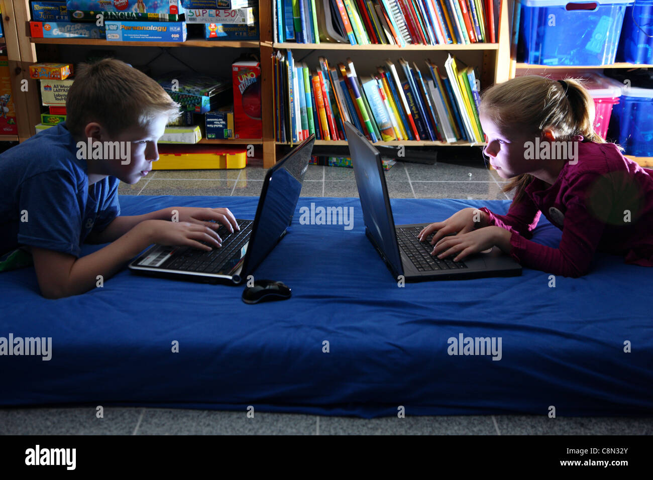 2 Bambini, ragazza 10, ragazzo di 13 anni, i giochi per computer su computer portatili, a casa. Foto Stock