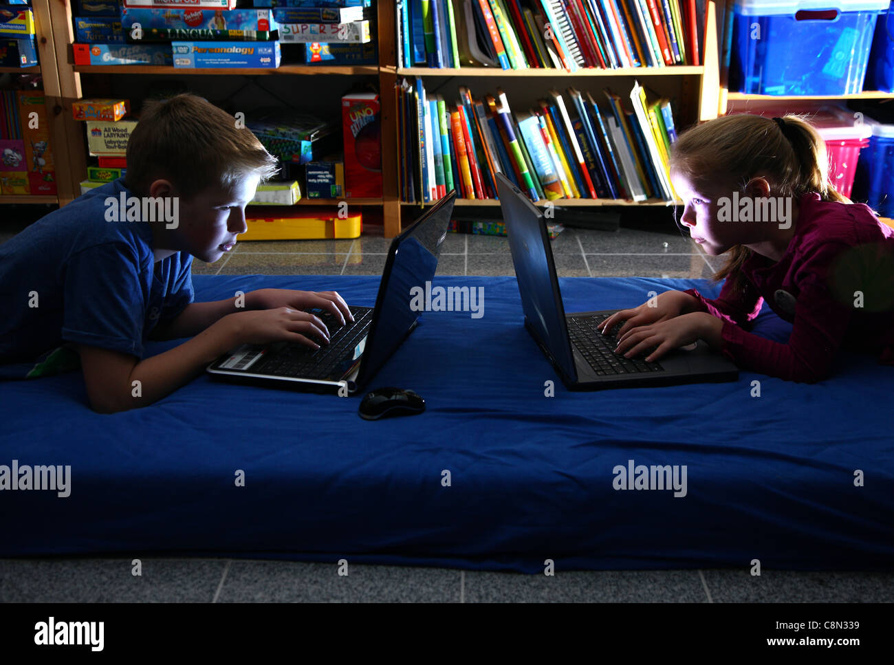 2 Bambini, ragazza 10, ragazzo di 13 anni, i giochi per computer su computer portatili, a casa. Foto Stock