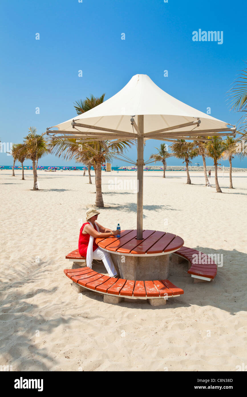 Turista femminile sotto ombrellone, palme, Jumeirah Russian Open Beach, Dubai, Emirati Arabi Uniti, Emirati arabi del Medio Oriente Foto Stock