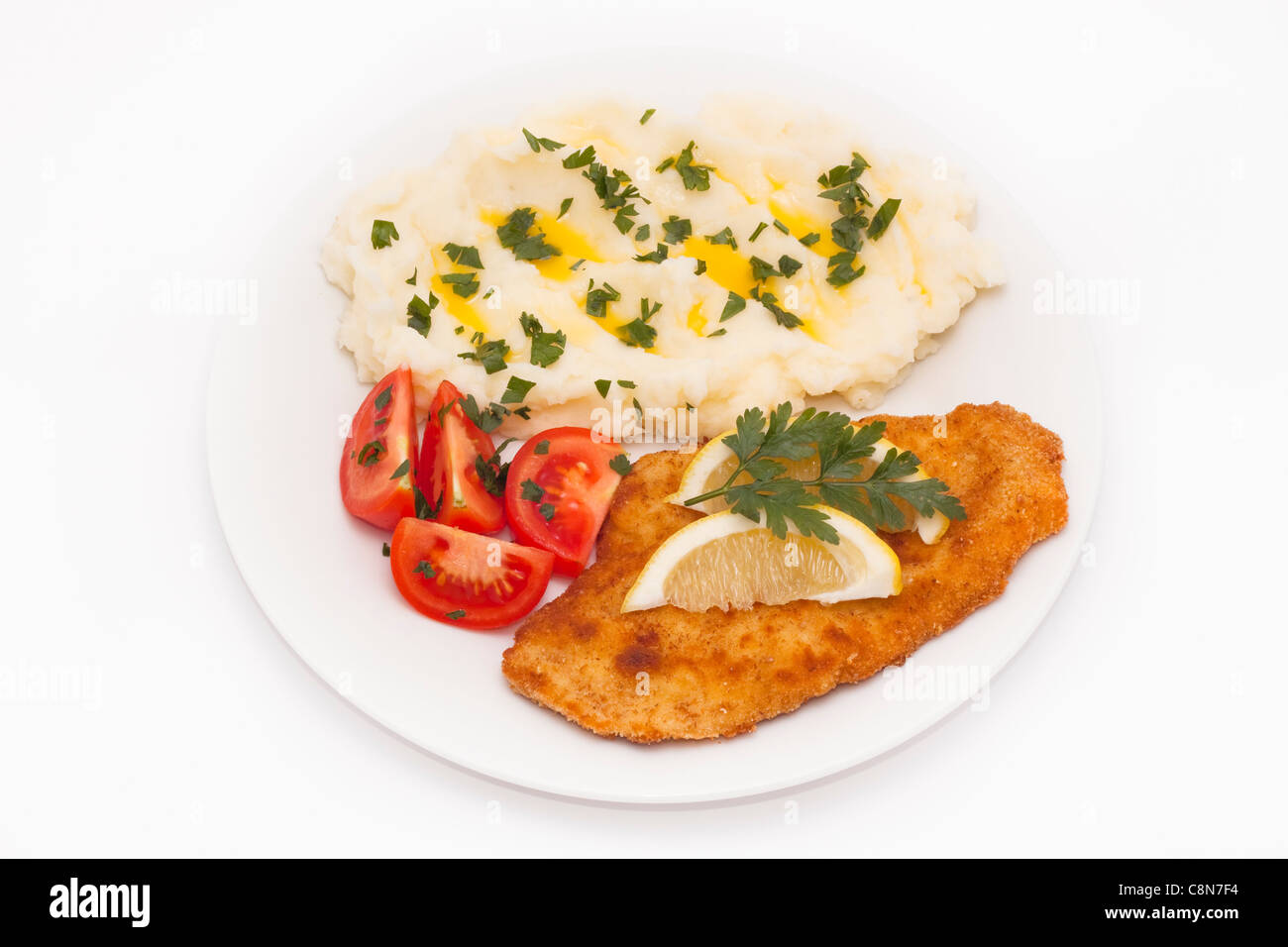 Cotoletta con limone, pomodori e purè di patate, isolato su sfondo bianco. Foto Stock