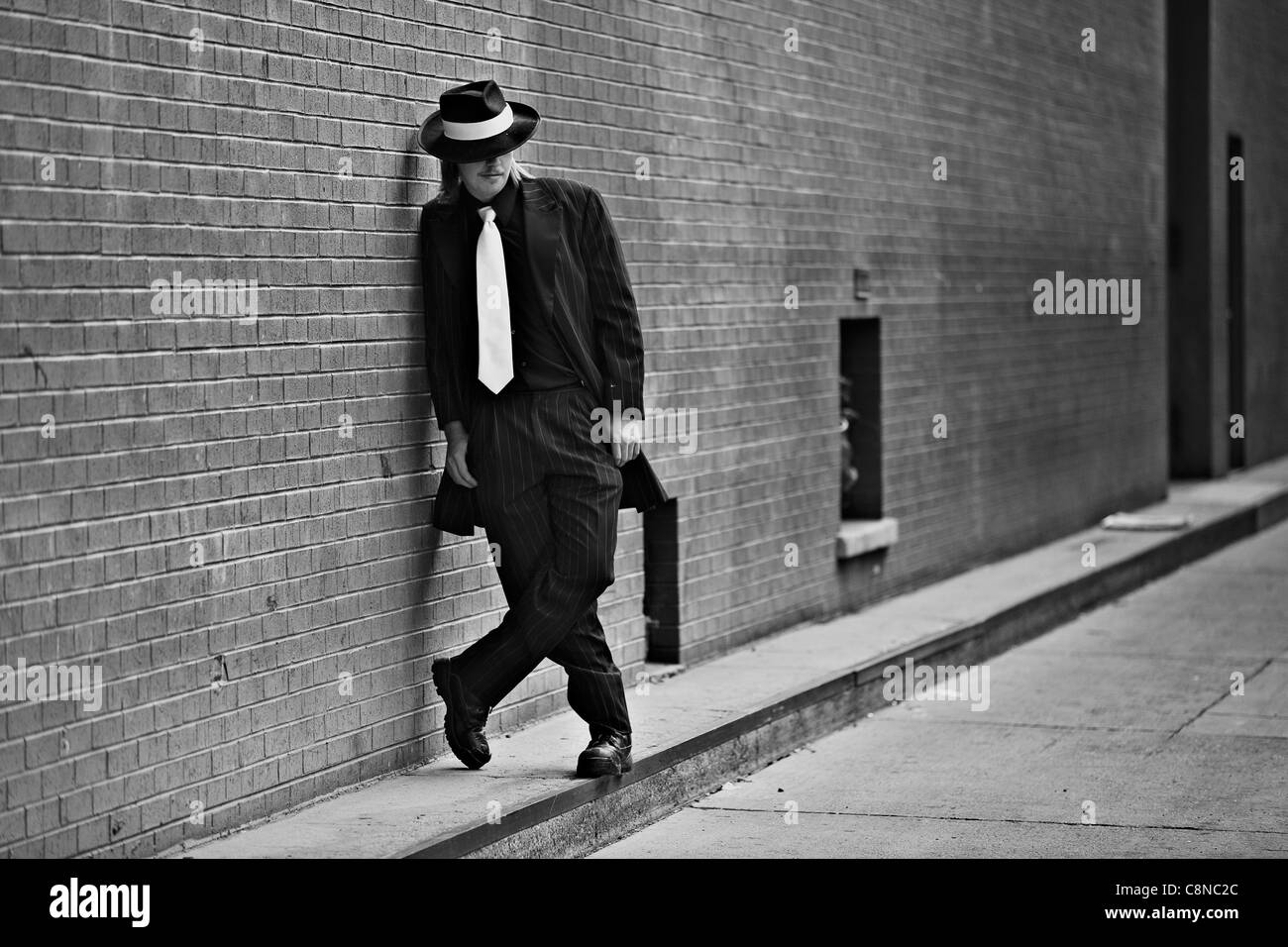 Immagine in bianco e nero di bel giovane uomo che indossa Zoot Suit prendendo in downtown. Foto Stock