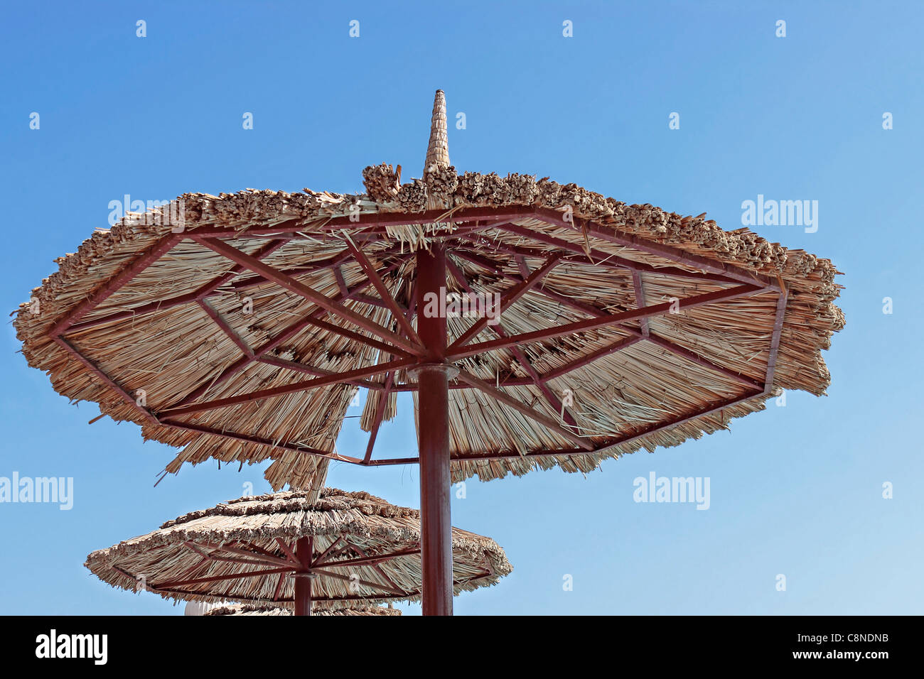 Acciaio a bordo piscina e reed ombrellone/parasol contro il cielo blu chiaro Foto Stock