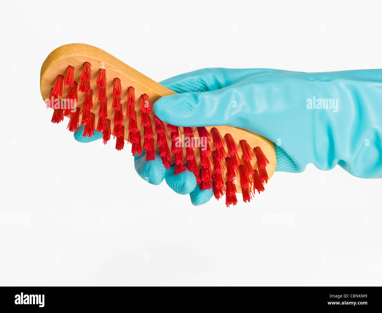 Una spazzola con setole di colore rosso è in possesso con i guanti di gomma Foto Stock
