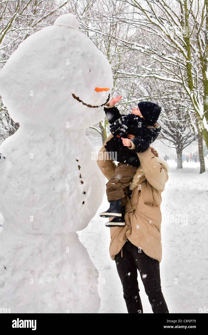 Mom aiutando il suo figlio per montare la carota di pupazzo di neve in Hyde Park. Foto Stock