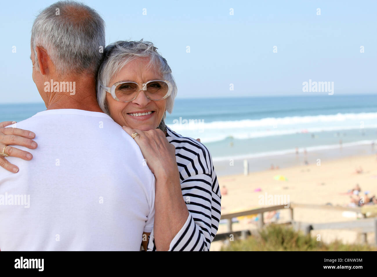 Un senior donna abbracciando il marito vicino al mare Foto Stock