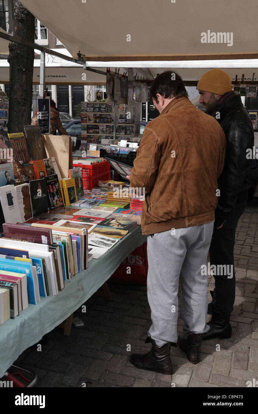 Due uomini guardando un libro in stallo il mercato delle pulci, Noordermarkt nel quartiere di Jordaan vecchia Amsterdam Holland Olanda Foto Stock