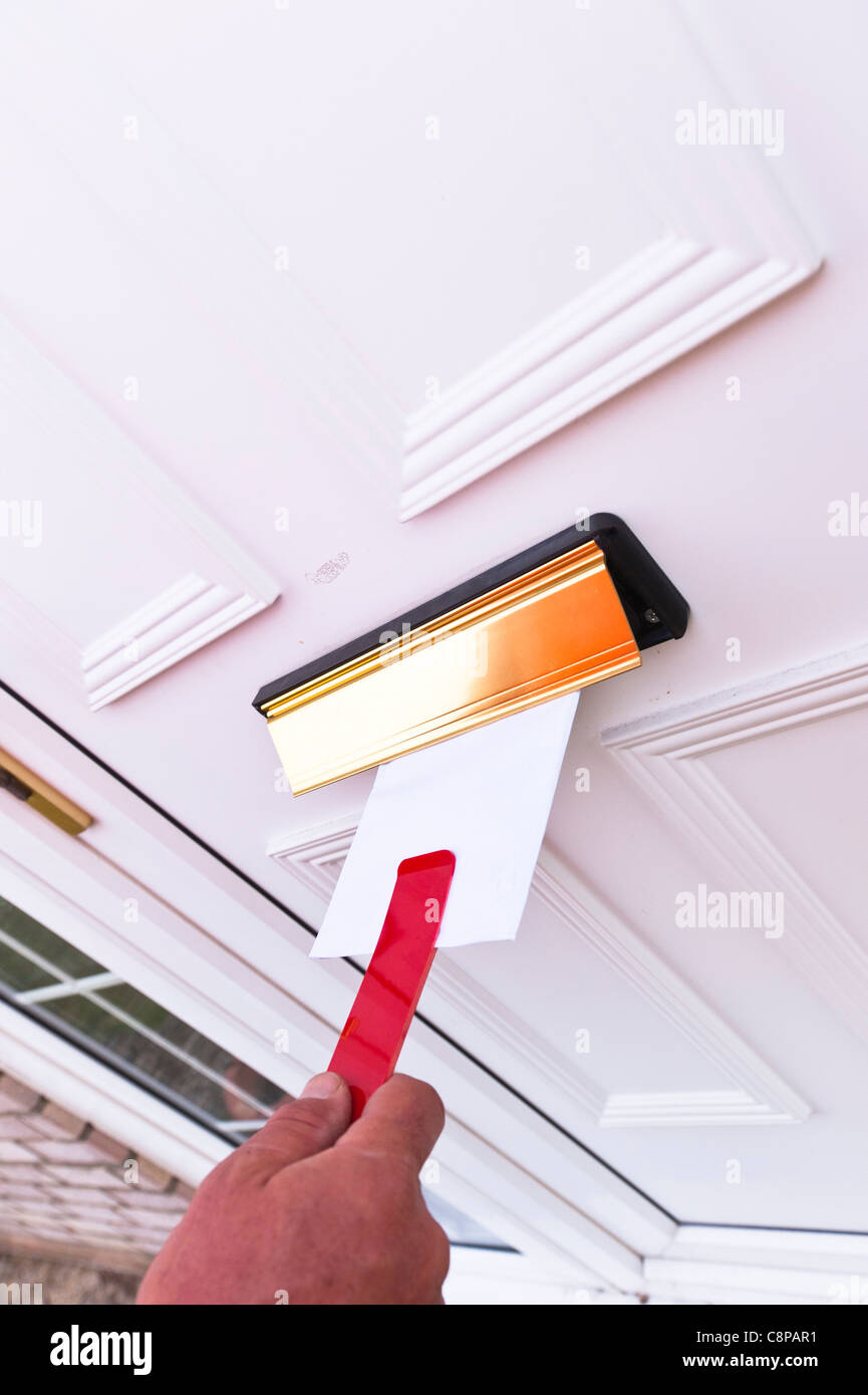 Un regno unito Royal Mail postino recapita una lettera utilizzando il nuovo strumento per fermare i cani di mordere le dita Foto Stock