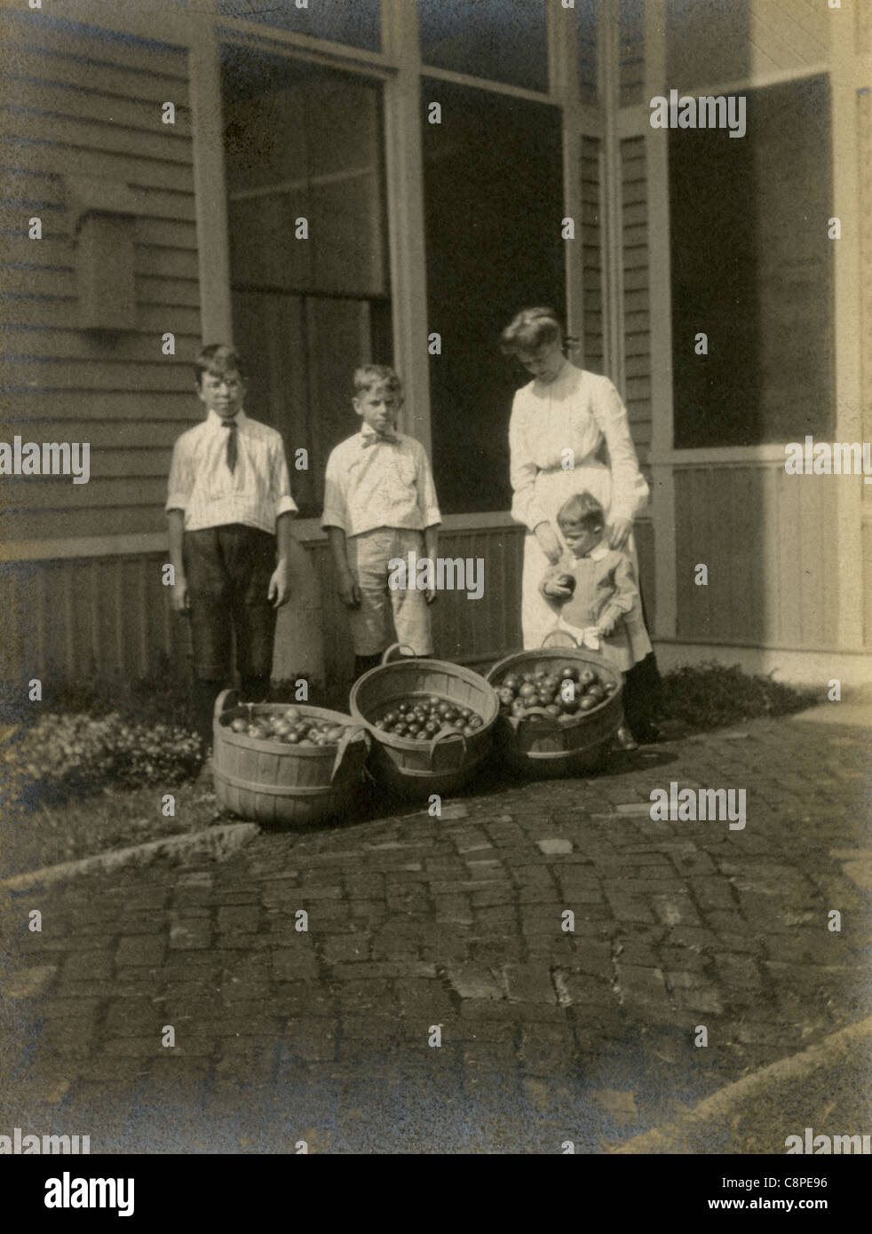 Circa 1910 fotografia di una madre e bambini con la loro piena cestini di apple. La Nuova Inghilterra, Stati Uniti d'America. Foto Stock