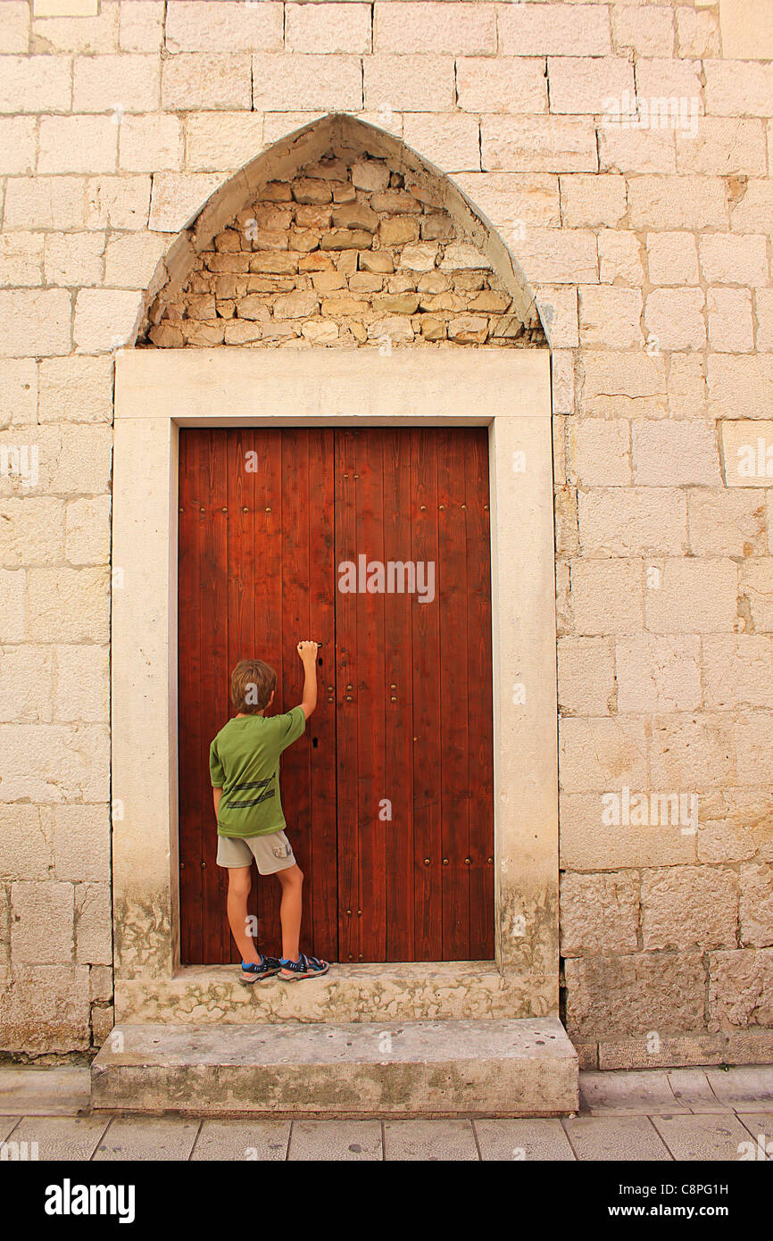 Un curioso giovane ragazzo in piedi di fronte ad una porta mistica Foto Stock