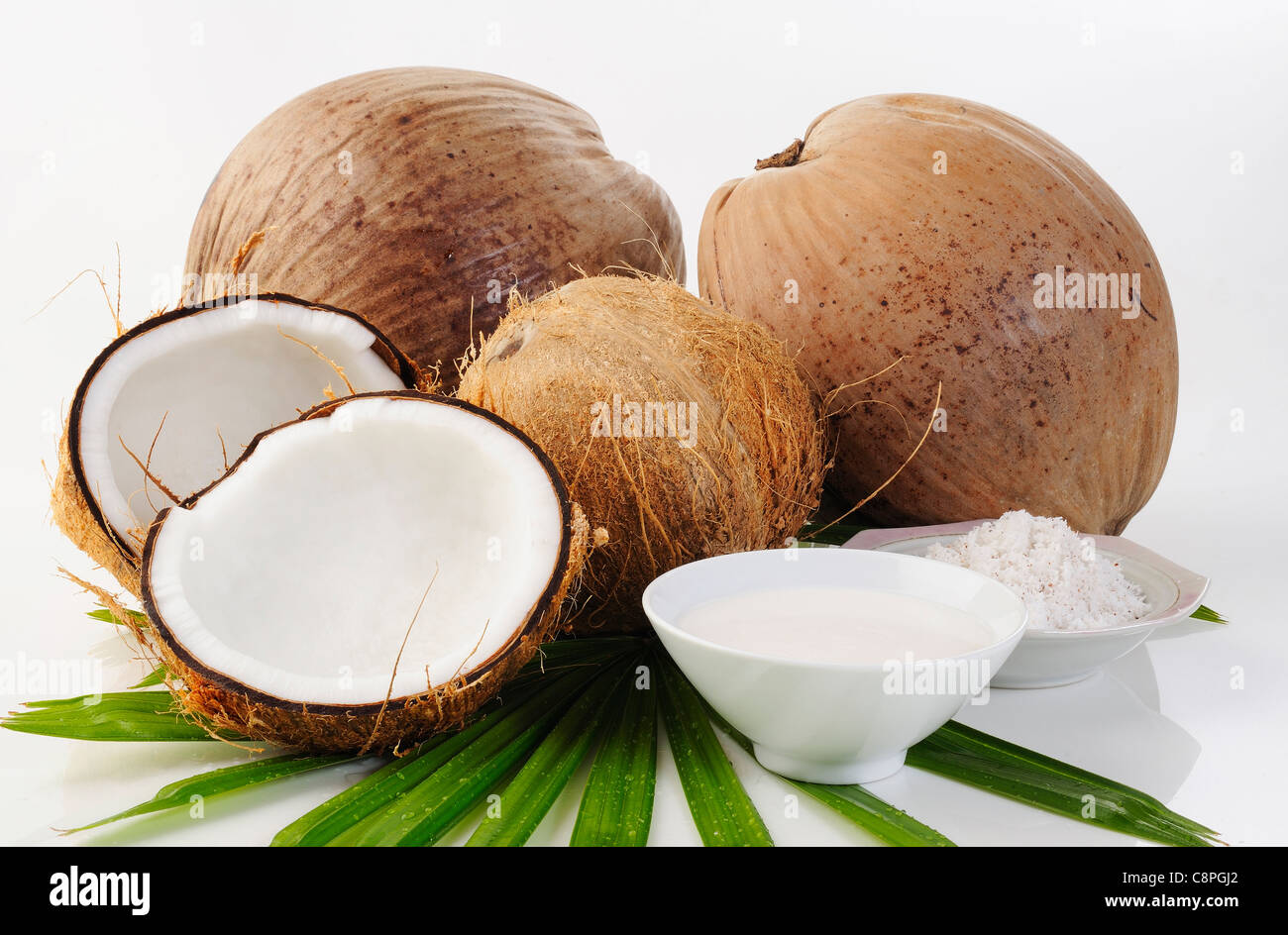 Noce di cocco, cocco grattugiato e crema di cocco su bianco Foto Stock