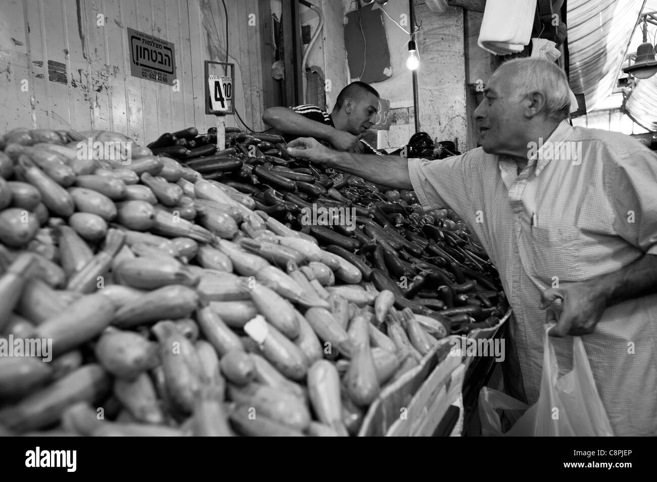 Un vecchio uomo caucasico scegliendo le verdure nel mercato. Foto Stock