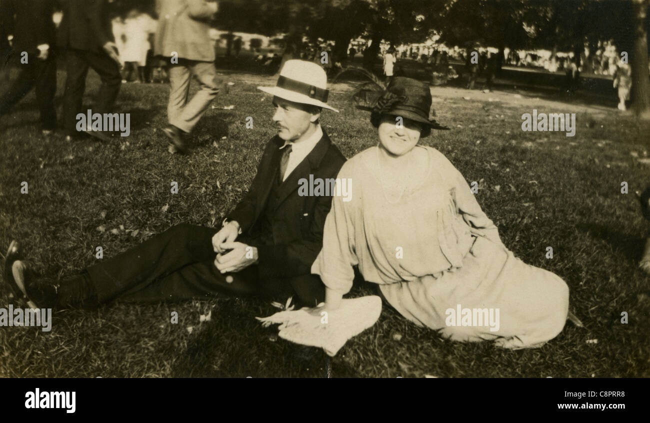 Circa 1910 foto di un uomo e di una donna seduta sul prato in un festival. Foto Stock