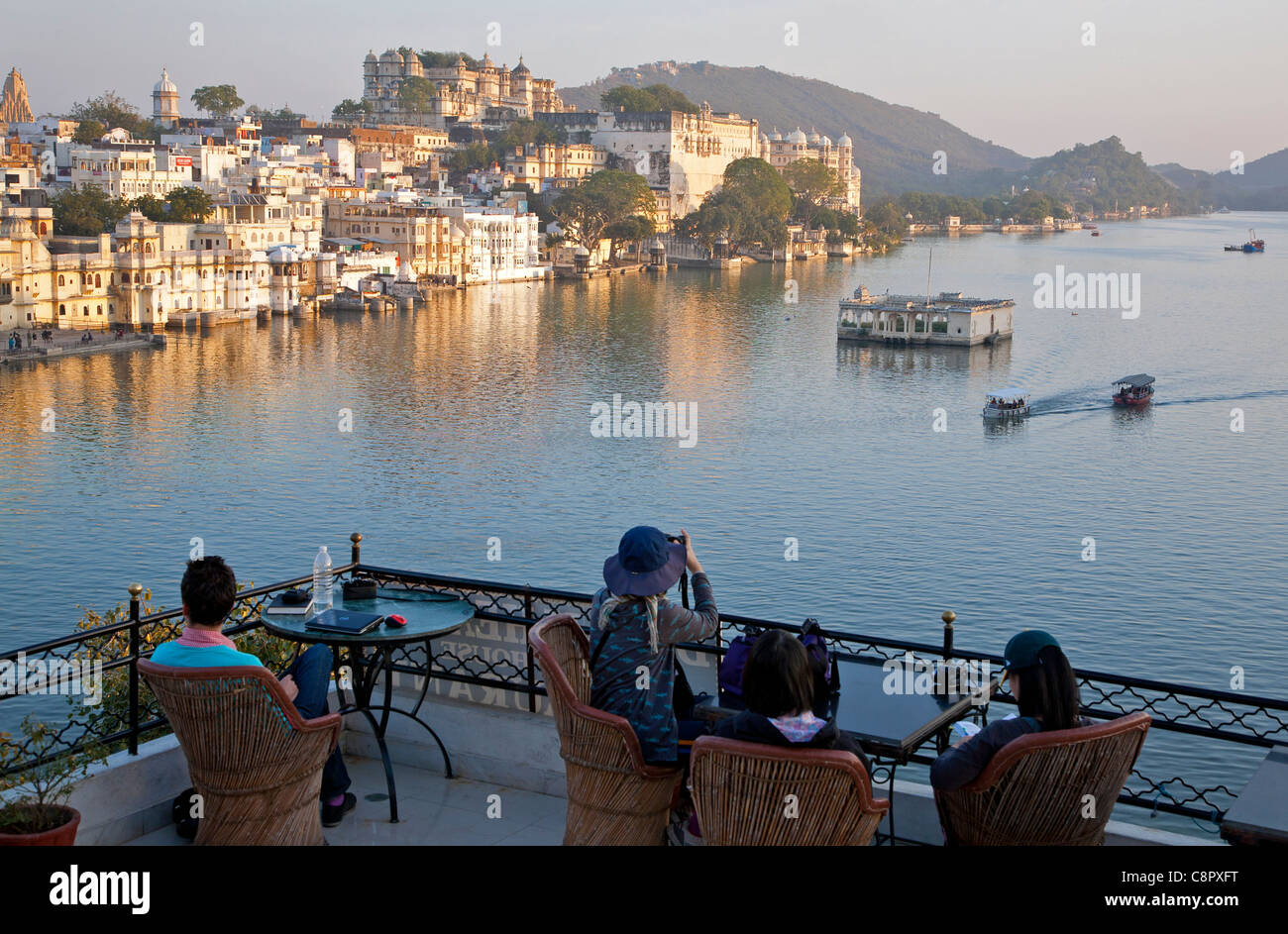 I turisti contemplando Lago Pichola da un ristorante sul tetto. Udaipur. Il Rajasthan. India Foto Stock