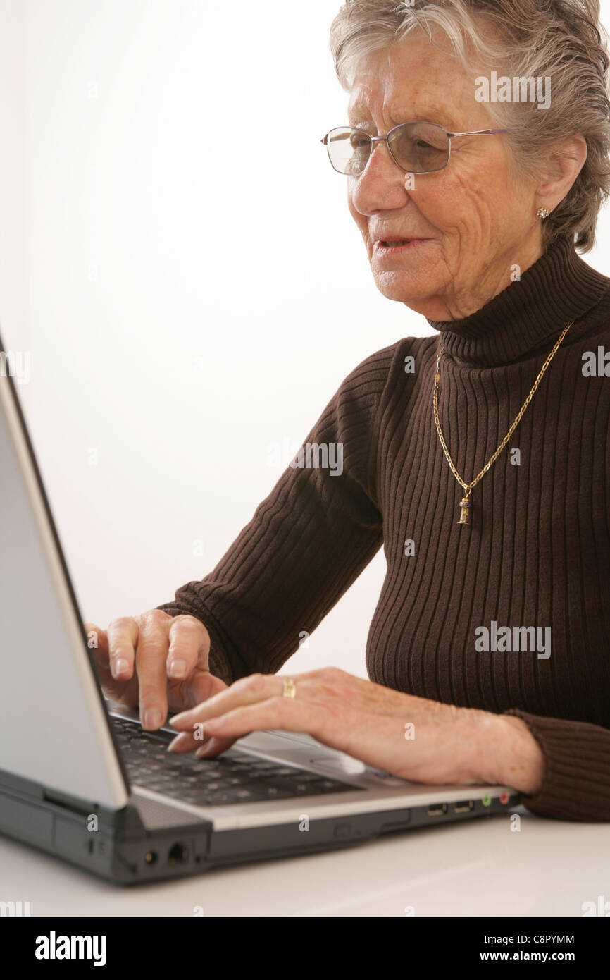 Donna anziana digitazione sul suo computer portatile. Foto Stock