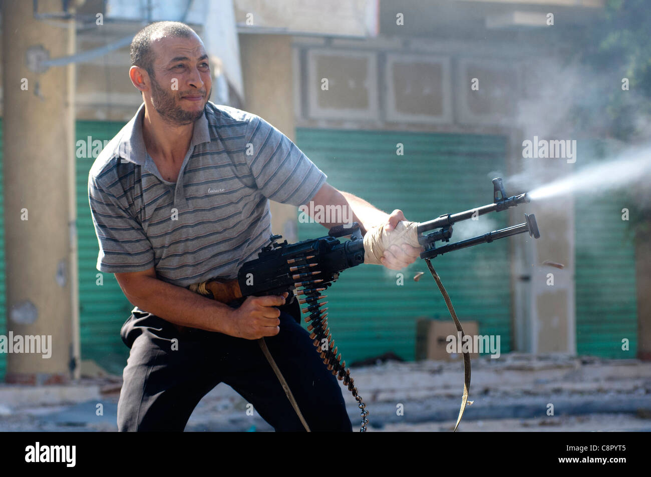 Rebel fighter battaglie cecchini nella piazza occupata dalle forze di Gheddafi sul finale il giorno della liberazione di Zarwiya Foto Stock