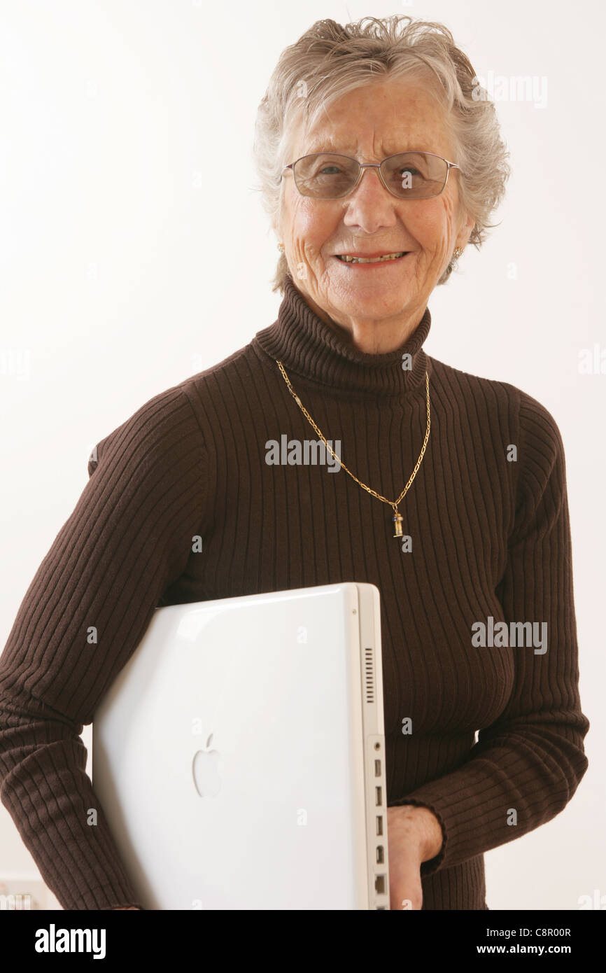 Donna anziana con il suo iBook laptop sotto il suo braccio. Foto Stock