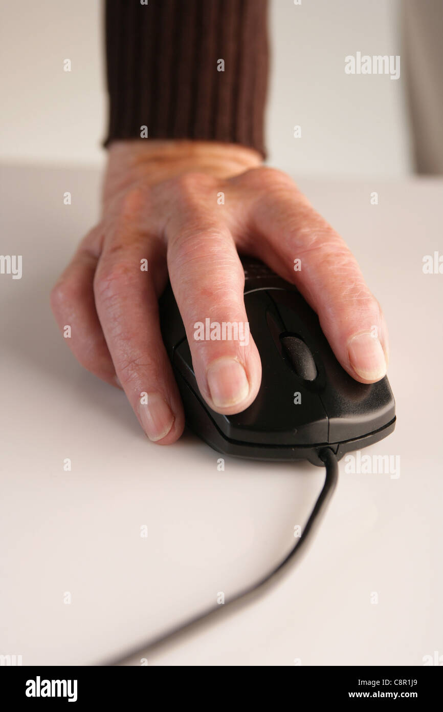 Una vecchia donna di mano utilizzando un mouse del computer. Foto Stock