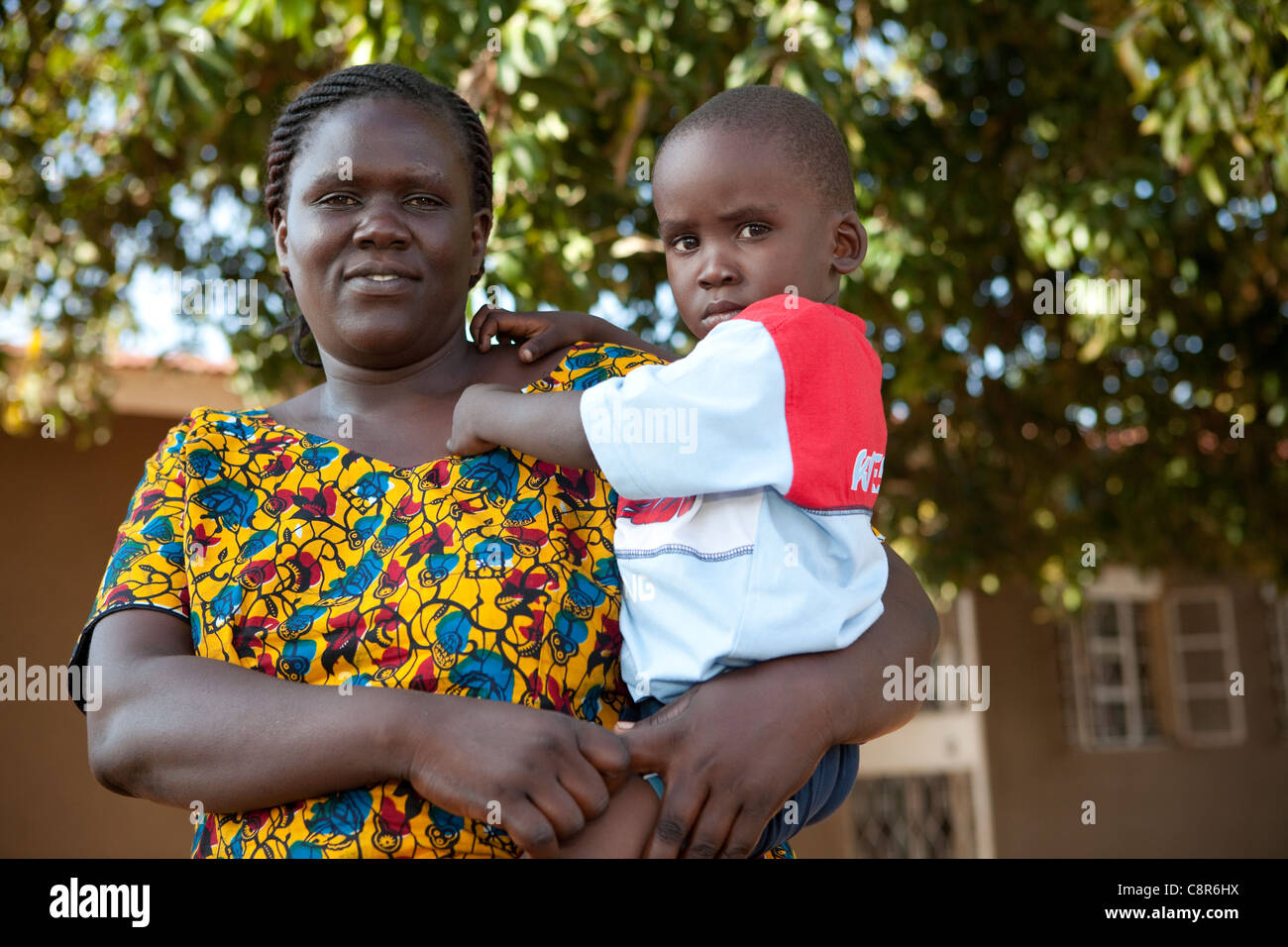 Una donna che tiene il suo bambino al di fuori di una violenza domestica vittima shelter in Pallisa, Uganda, Africa orientale. Foto Stock