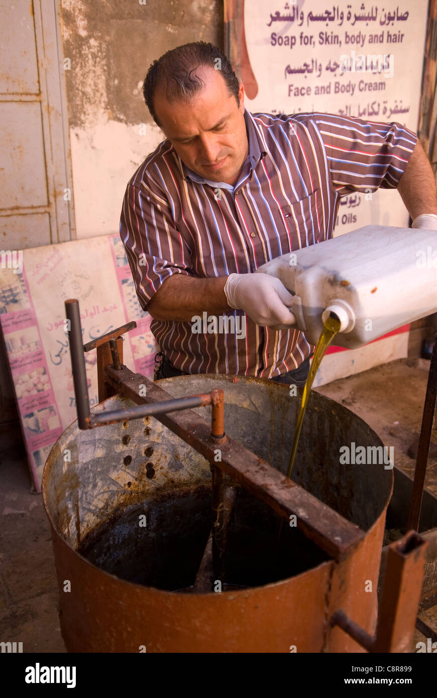 Sapone maker versando olio d'oliva in un tamburo; l'ingrediente essenziale nella produzione di sapone, souk, Tripoli, nel nord del Libano. Foto Stock