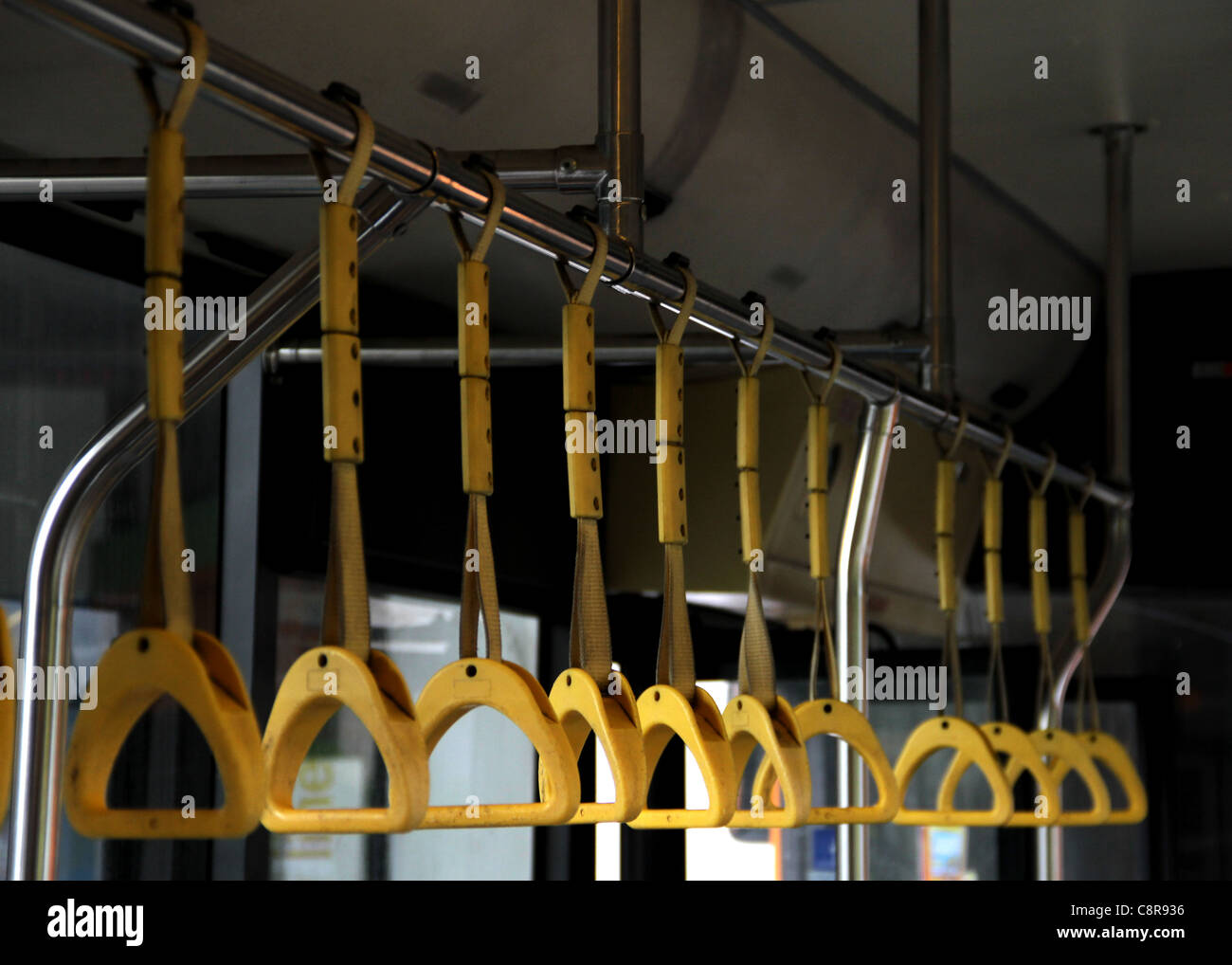 Fila di giallo le maniglie di appiglio per i passeggeri in piedi all'interno di un pullman Foto Stock