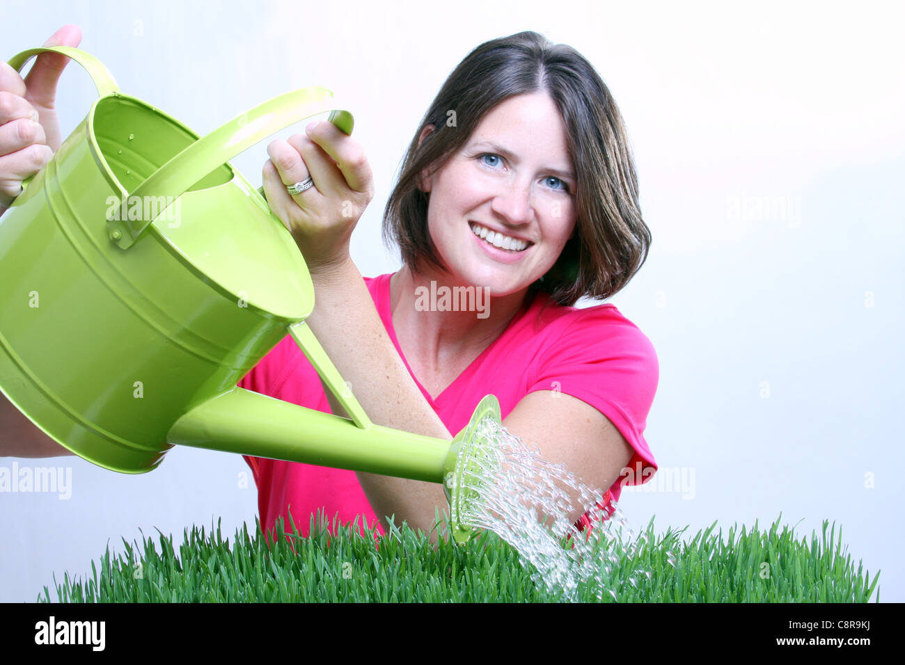 Una donna con un annaffiatoio a erba acqua focus sull'acqua Foto Stock