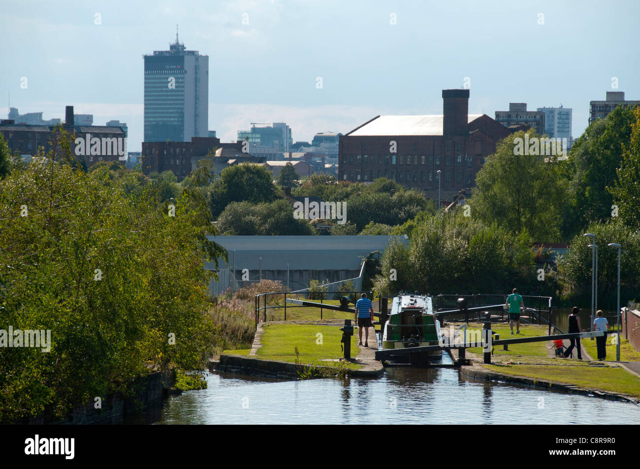 Un narrowboat in un blocco sull'Ashton Canal, Clayton, Eastlands, Manchester, Inghilterra, Regno Unito. City Tower (Piccadilly Plaza) dietro. Foto Stock