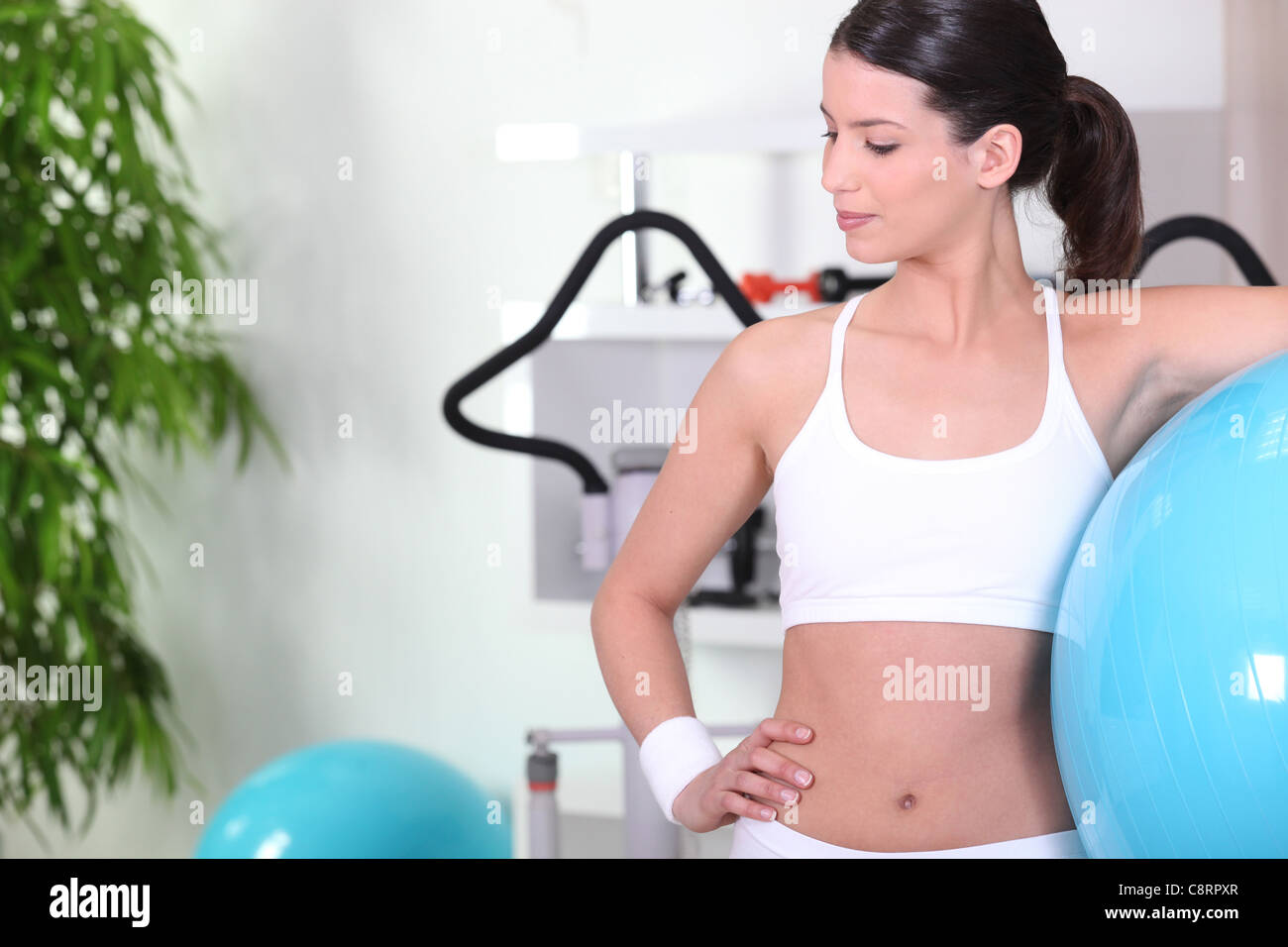 Donna in piedi con una palla ginnica in palestra Foto Stock
