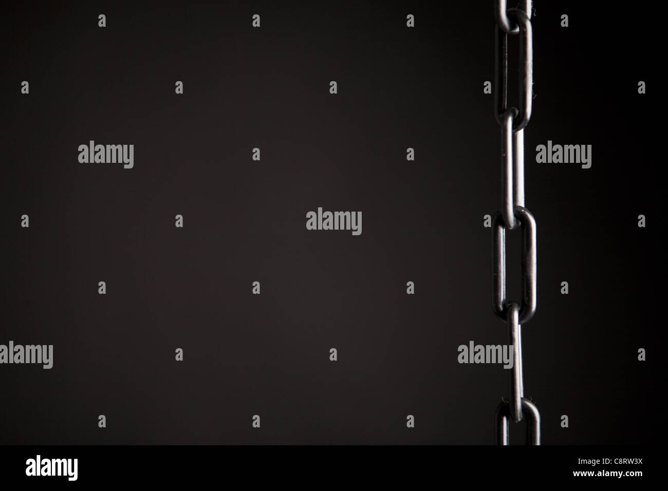 Una immagine minima di una catena di plastica nero su sfondo nero per dare un messaggio concettuale sui collegamenti Foto Stock