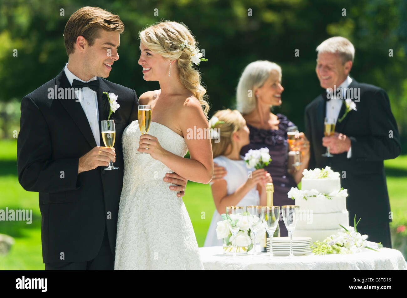 Stati Uniti d'America, nello Stato di New York, Old Westbury, sposi azienda flute da champagne, gli ospiti in background Foto Stock