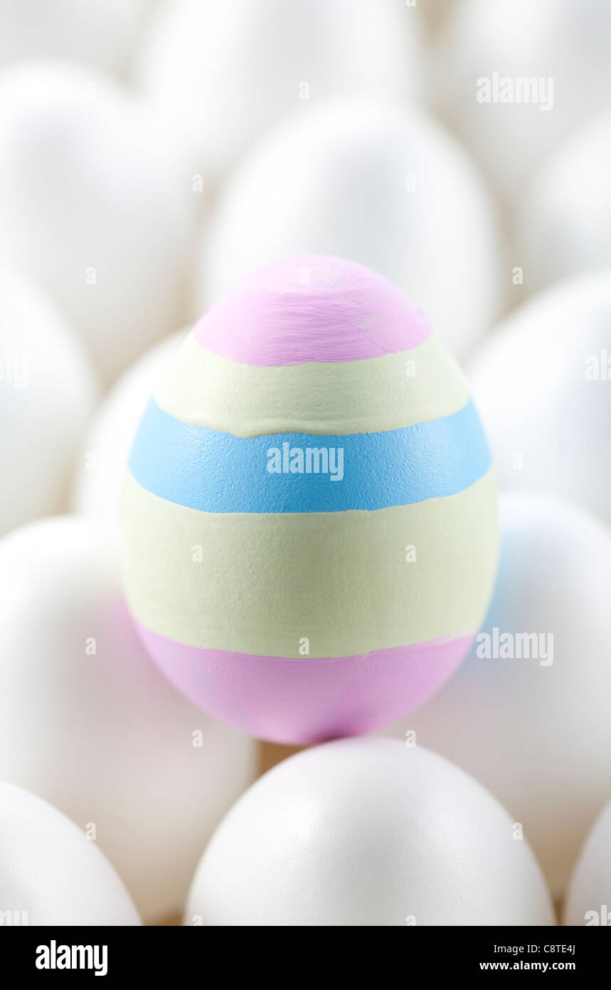 Uno colorato uovo di pasqua tra quelli bianchi su uovo Foto Stock