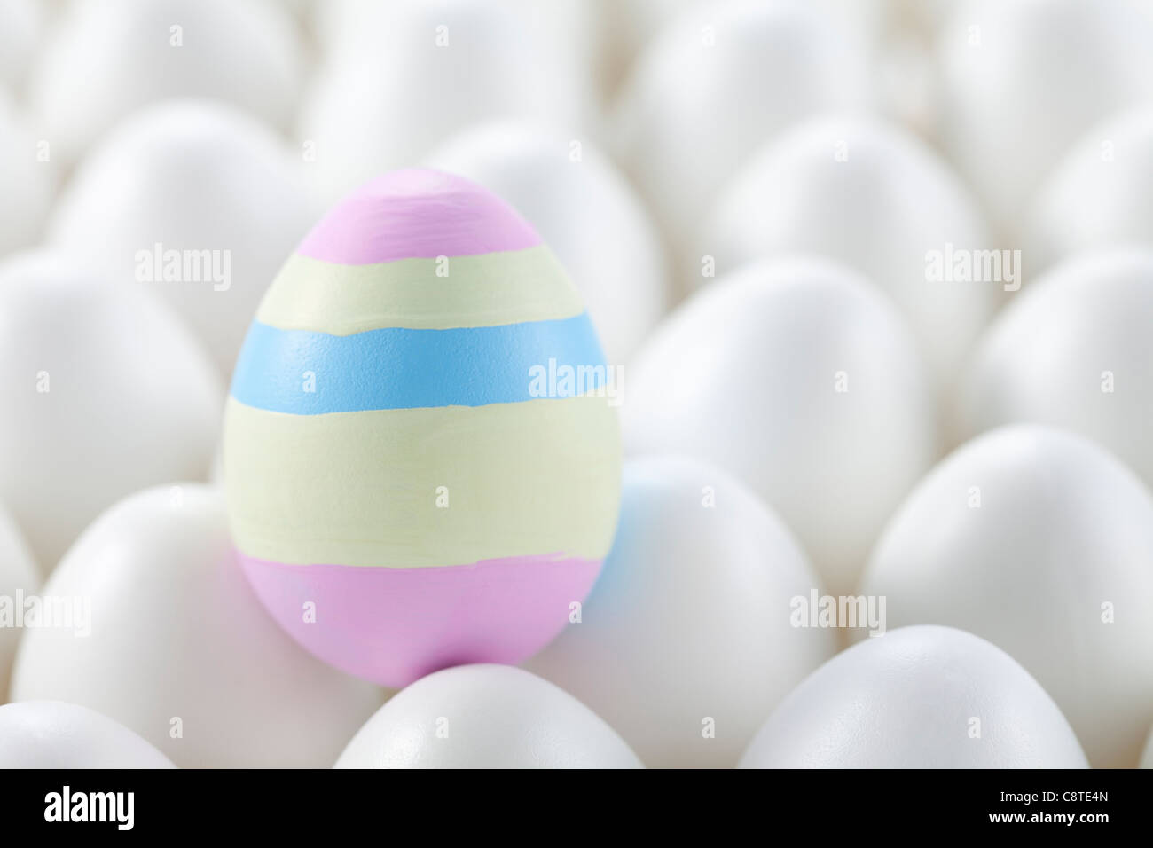 Uno colorato uovo di pasqua tra quelli bianchi su uovo Foto Stock