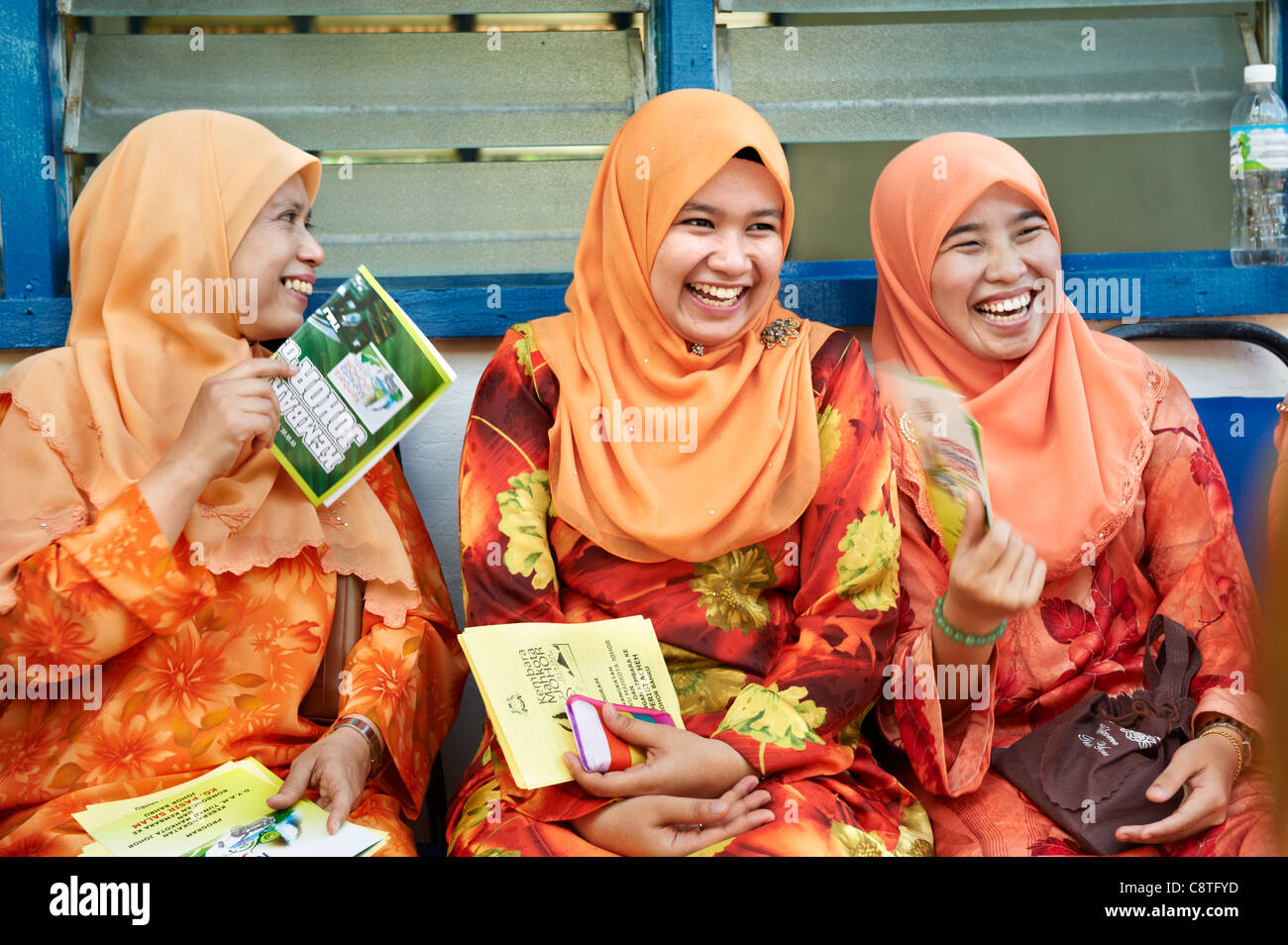 Tre malesi le donne sono vestiti con i loro tradizionali usura e ridere per uno scherzo. Foto Stock