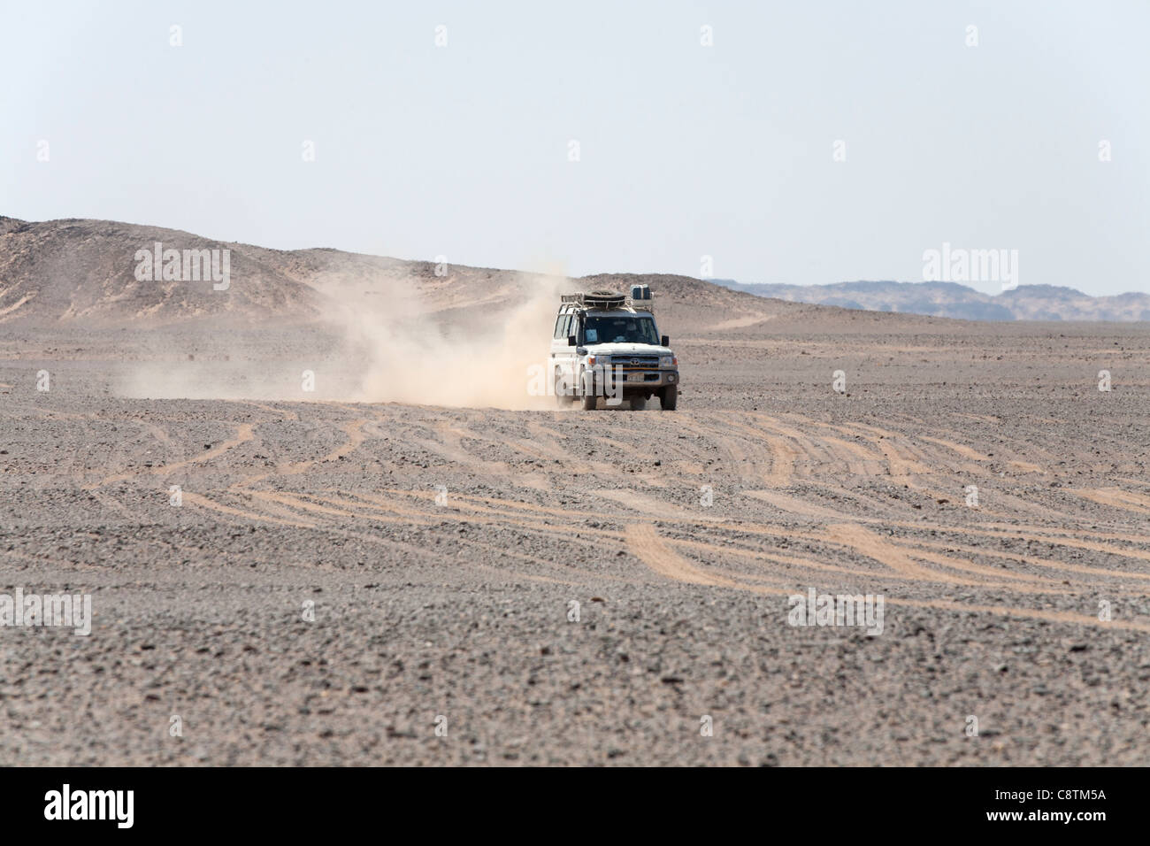 Colpo lungo di quattro ruote motrici avvicinando la fotocamera calci su sentieri di polvere in Egitto e nel deserto orientale Foto Stock